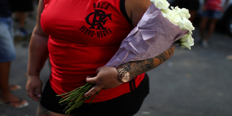 Mulher com flores brancas em enterro de jovem que morreu no incêndio no CT do Flamengo